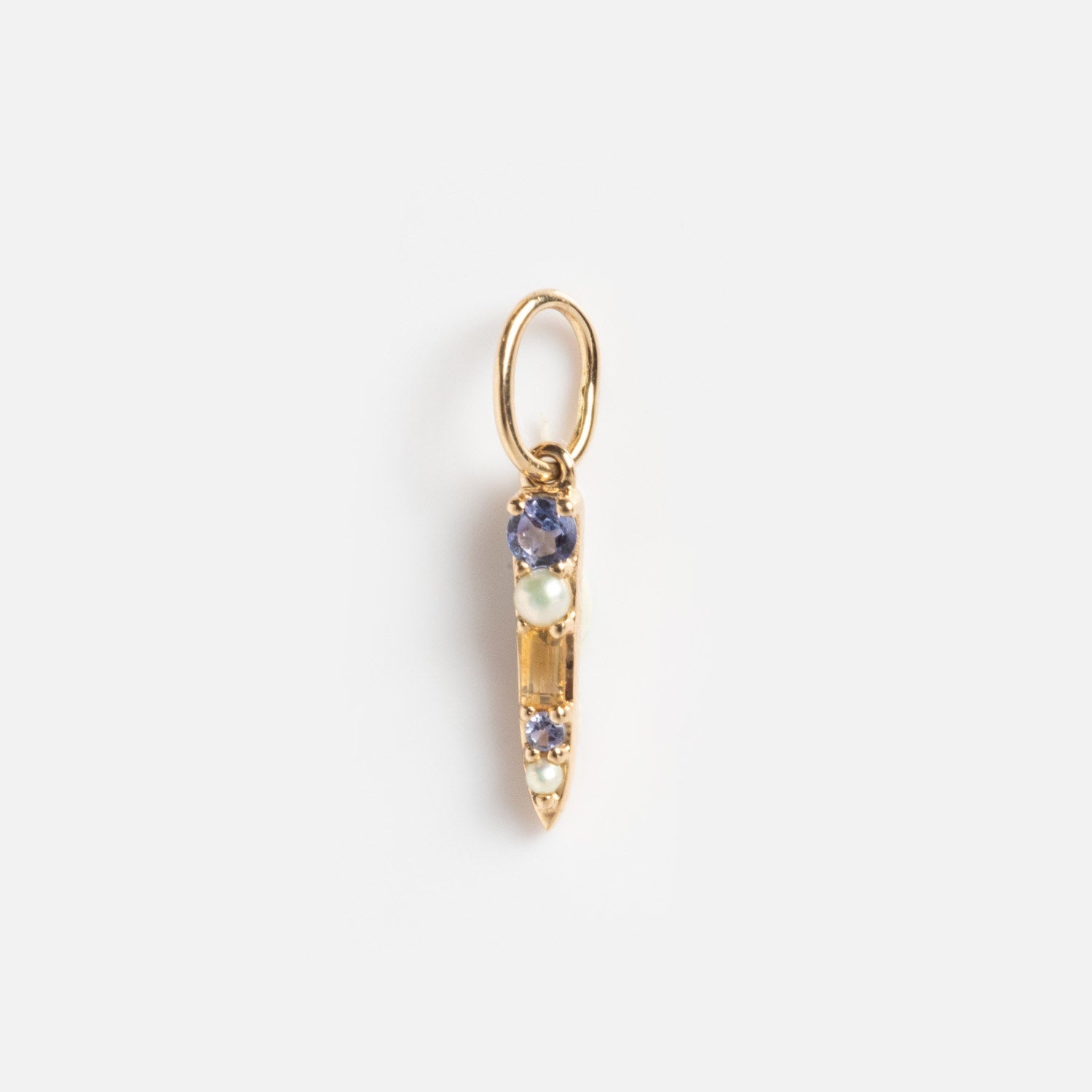 The Solid Gold Statement Charm is a small gold pendant with a pointed tip and three vertically set gemstones—two purple, one white. Attached to a round gold loop, it's ideal for statement necklaces or solid gold charm collections.