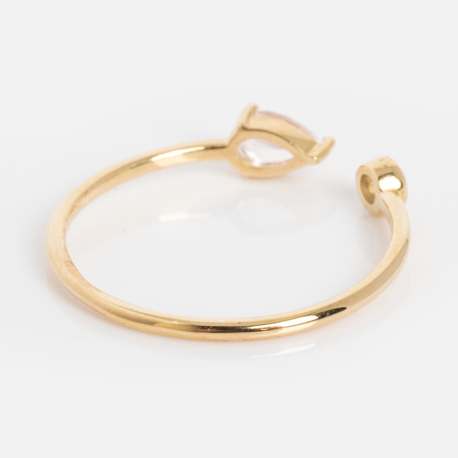 The Solid Gold Sapphire and Aquamarine Open Front Ring features a marquise-cut light pink gemstone on one end and a small circular accent on the other, elegantly displayed on a white background.