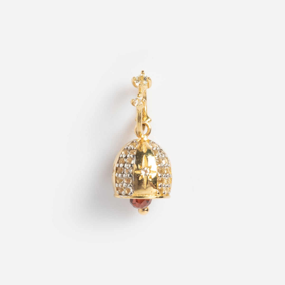 The Solid Gold Celebration Charm is a gold earring shaped like a domed lamp, featuring small white stones and a red bead inside, reminiscent of engraved gold charms, shown against a plain white background.