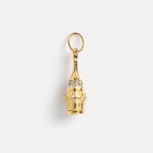 The Solid Gold Celebration Charm is a 9k gold piece shaped like a champagne bottle, featuring clear stones around the neck and a gold loop for hanging, photographed on a plain white background.