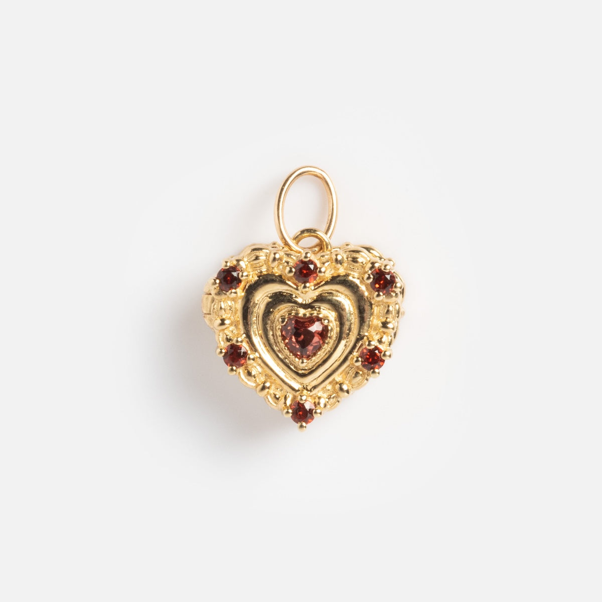 The Solid Gold Celebration Charm is a heart-shaped pendant in 9k gold, featuring a central red gemstone and five smaller red stones around the edge, highlighting its intricate design against a plain white background.