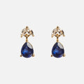 The Solid Gold 2025 September Capsule Classic Blue Sapphire Stud Earrings feature teardrop blue sapphires below two marquise-cut white topaz stones, all set in 9k yellow gold against a plain white background.