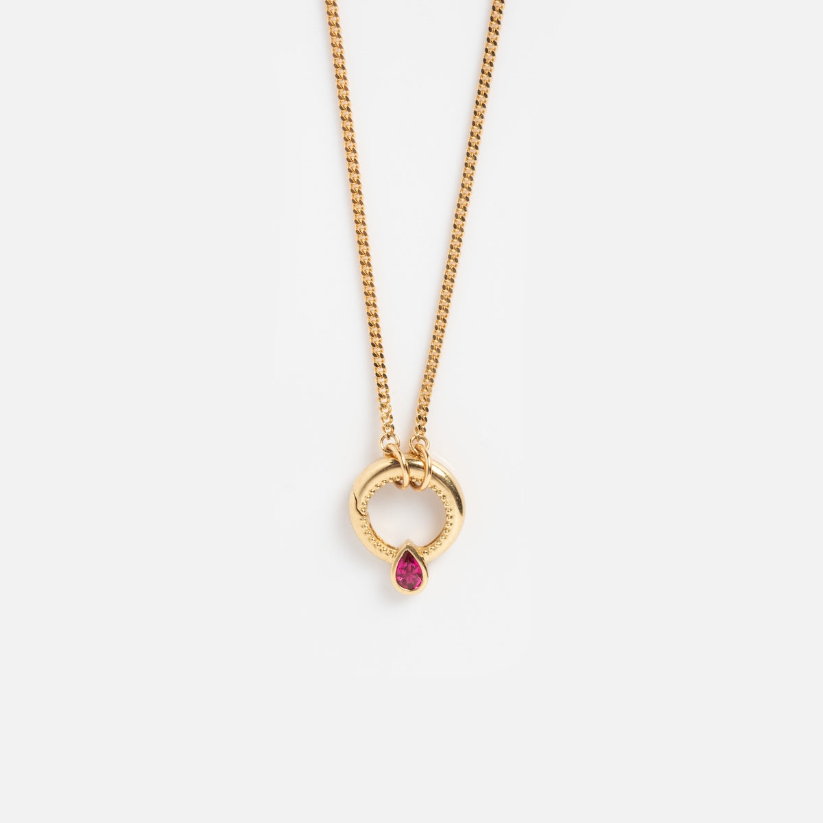 The Solid Gold Perfect Start Charm Holder Necklace features a circular pendant on a gold chain, with a teardrop-shaped pink gemstone in the center, displayed against a plain white background.