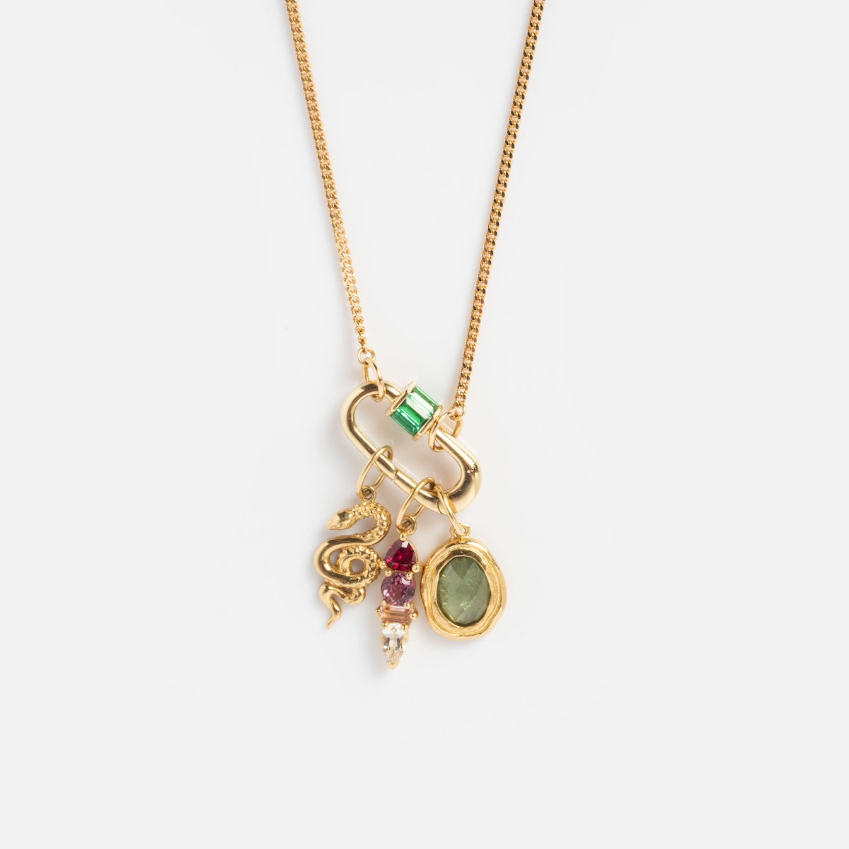 The Solid Gold Perfect Start Charm Holder Necklace features a gold chain with four charms: a green rectangular gem, a gold dragon, red and pearl bead cluster, and an oval green stone set in gold, shown on a plain white background.