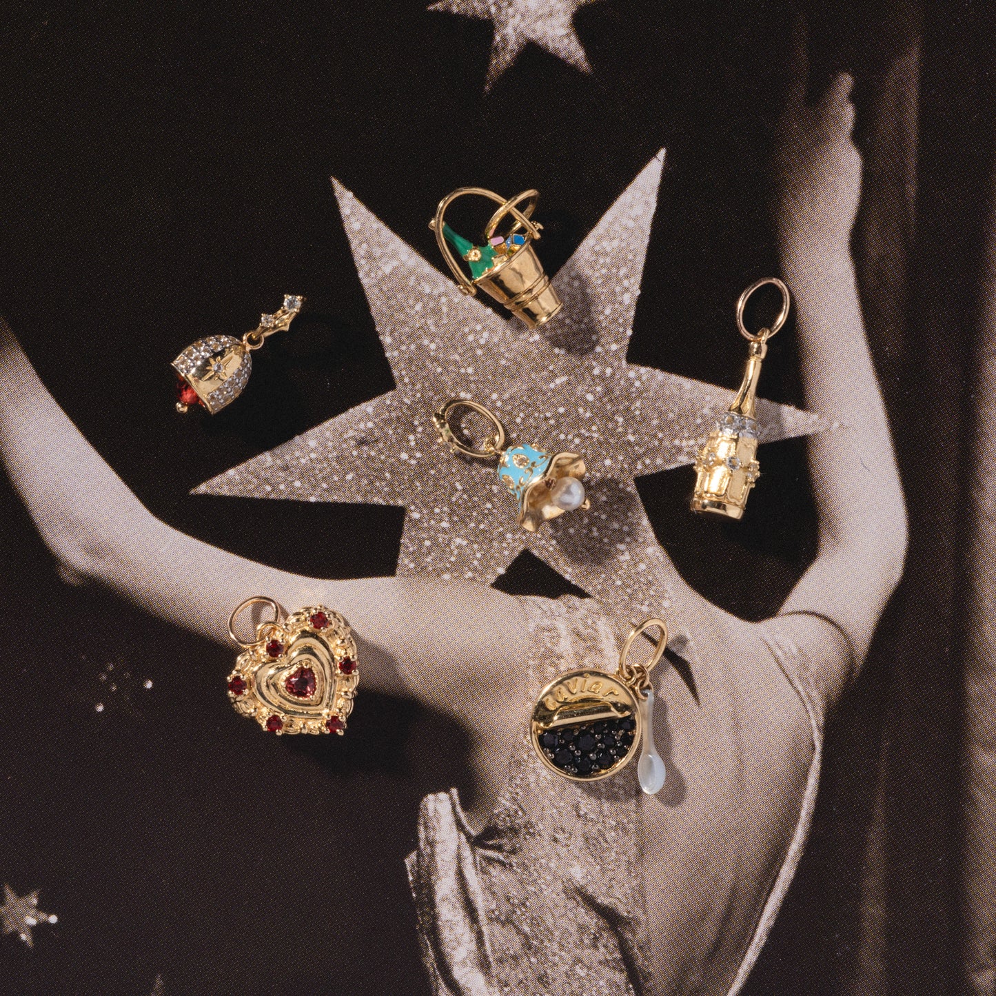 Six ornate Solid Gold Celebration Charms, featuring hearts, gemstones, and a small ship, are showcased on a vintage-style photo of someone in a sparkling dress with a star pattern on the back.