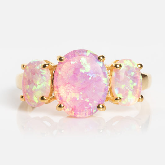 The Pink Opal Gum Drop Ring features three oval pink opals with an iridescent sheen in prong settings, displayed on a white background.