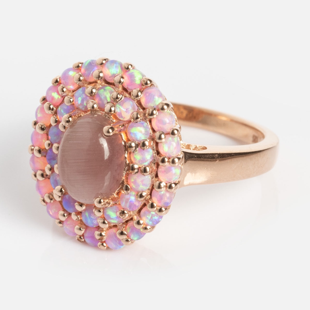 The Rose Gold Pink Opal and Cats Eye Moonstone Crown Ring showcases a large oval pink gemstone, accented by two rows of iridescent opal beads in an elegant halo crown setting.