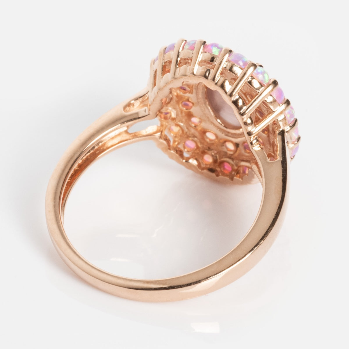 The Rose Gold Pink Opal and Cats Eye Moonstone Crown Ring showcases a round setting with iridescent pink opals encircling the center, viewed from below, with intricate open lattice details in the gallery.