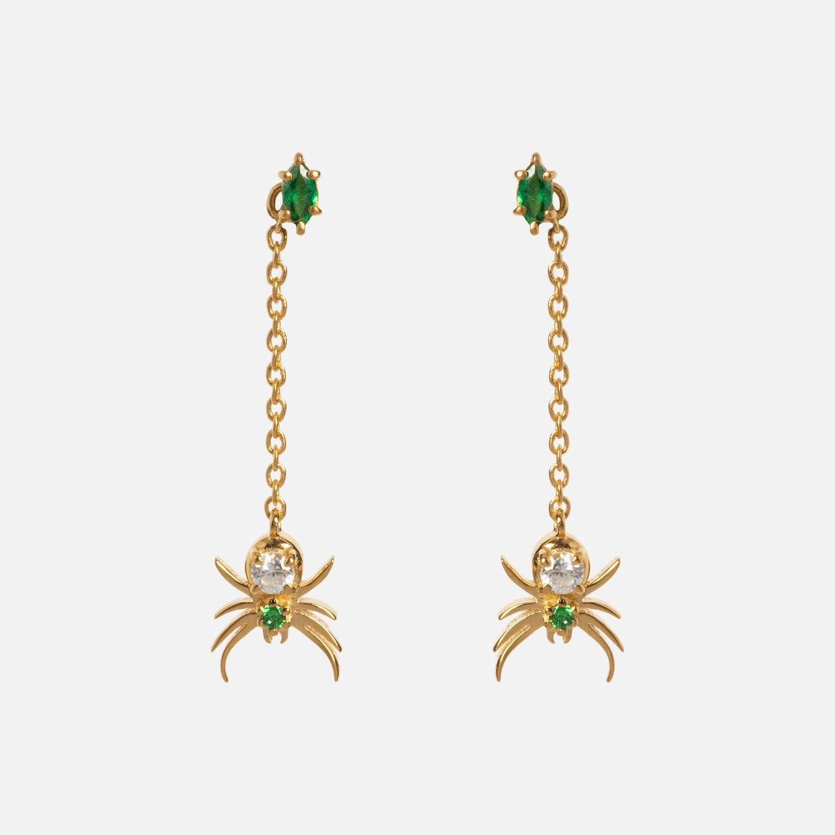 The Limited Edition Tangled Webs Spider Drop Earrings feature gold chains with dangling spider charms, each adorned with green gemstones at the stud and in the spider’s body.
