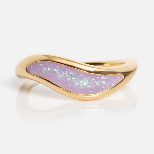 The Opal Dreamers Wave Ring showcases a gold band with a wavy design and an iridescent light purple opal inlay, set against a plain white background.