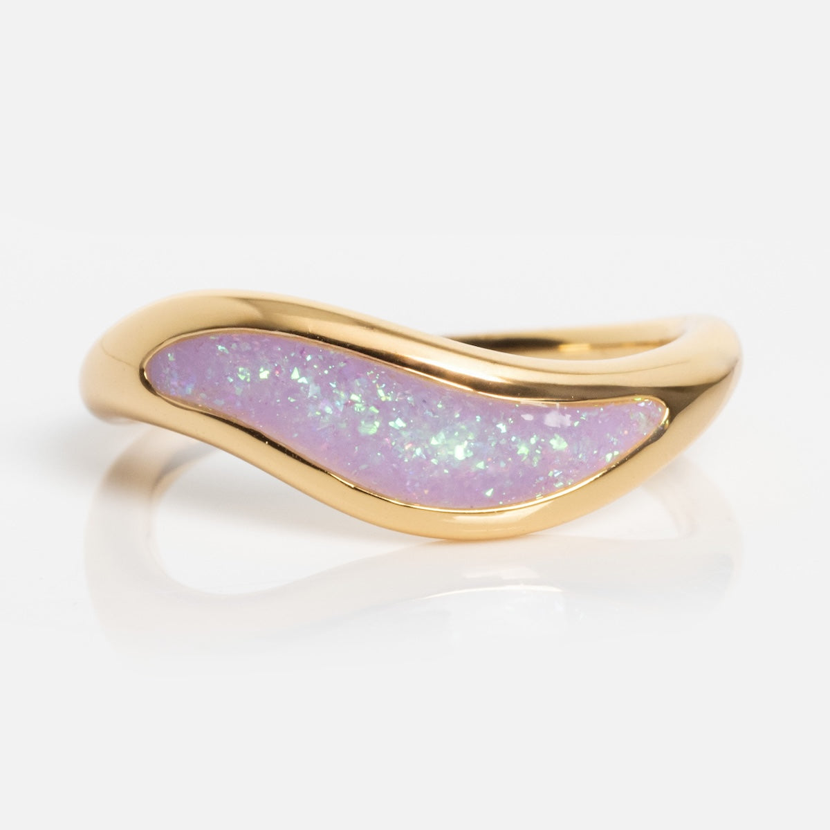 The Opal Dreamers Wave Ring showcases a gold band with a wavy design and an iridescent light purple opal inlay, set against a plain white background.