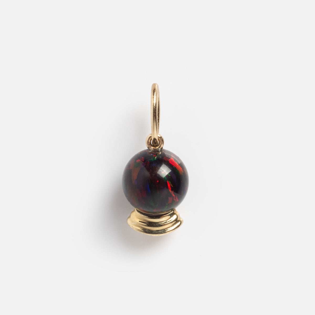 The Limited Edition Solid Gold Halloween Superstitions Charm features a dark, glossy orb with red streaks on a small gold stand and loop, perfect for attaching to a necklace. Shown against a plain white background.