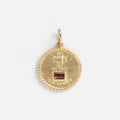 The Solid Gold Coin Charm is a round solid gold charm with a small gemstone at the top, an inset rectangular red stone near the bottom, and 