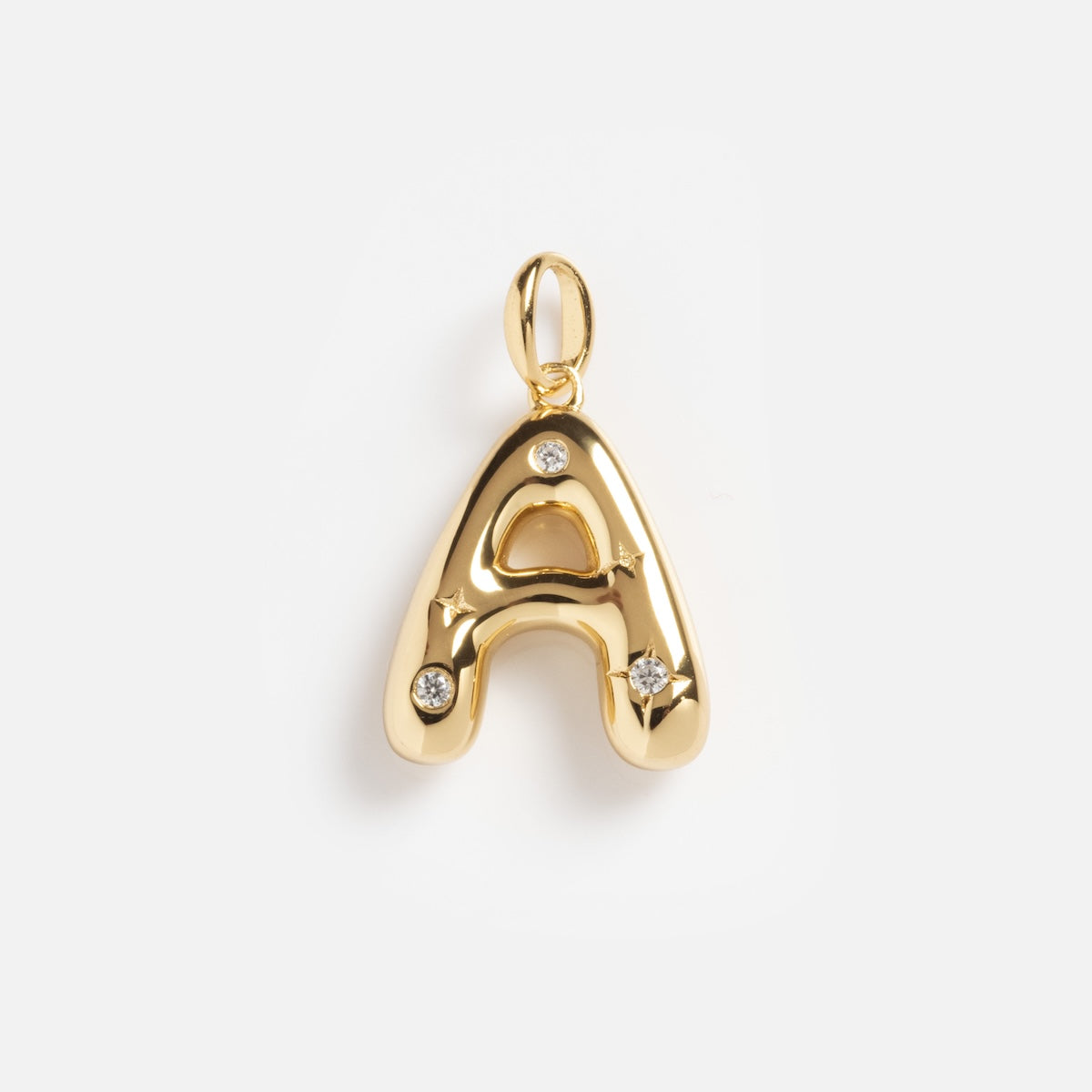 The Star Crossed Celestial Bubble Letter Charm is a gold pendant shaped like the letter A, featuring three small, round clear gemstones, shown against a plain white background.