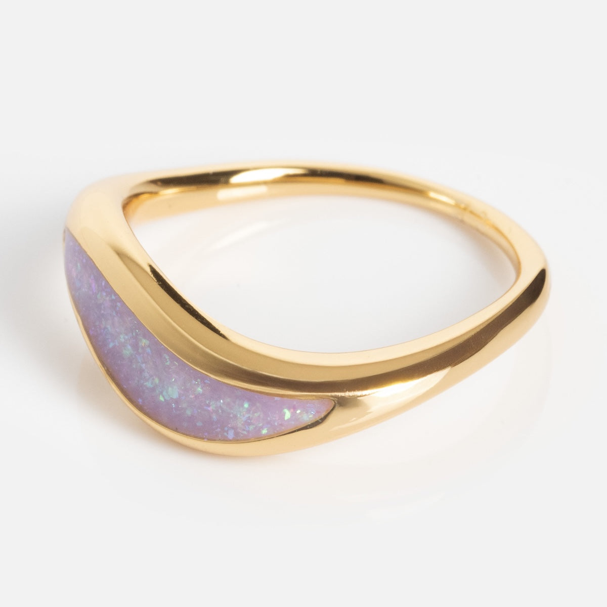 The Opal Dreamers Wave Ring is a gold ring with a smooth, curved design and an inlaid section of iridescent purple opal, shown on a white background.