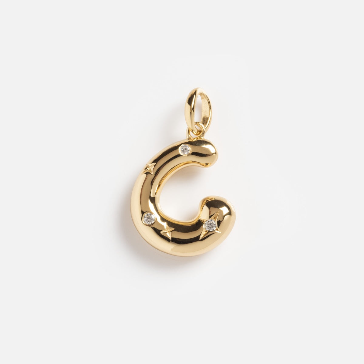 The Star Crossed Celestial Bubble Letter Charm is a shiny gold “C” charm adorned with small star-shaped details and clear gemstones, shown against a plain white background.