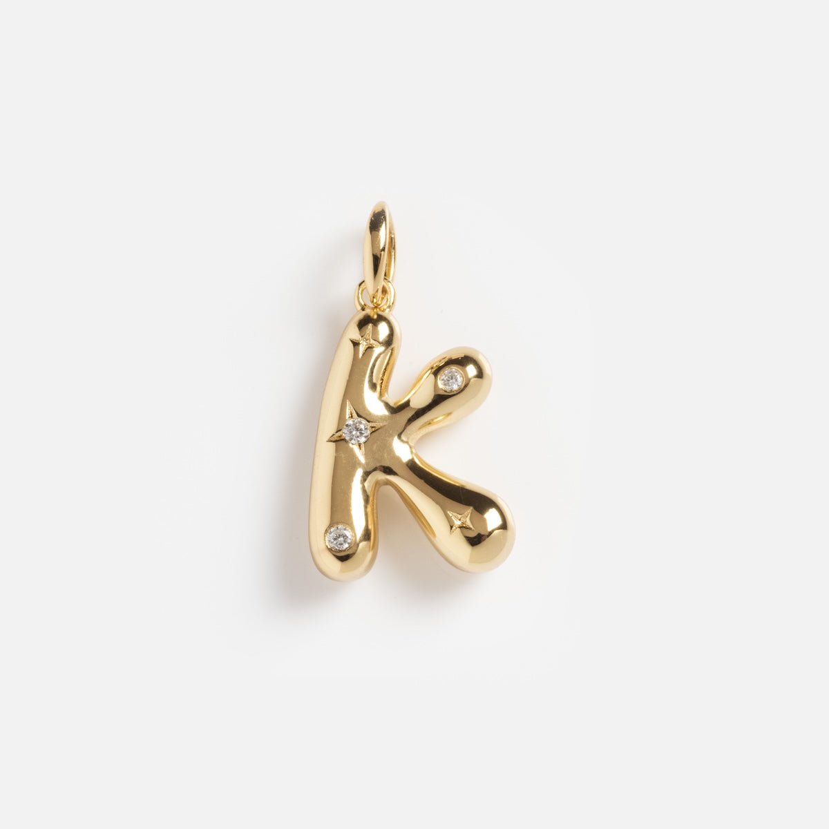 The Star Crossed Celestial Bubble Letter Charm is a gold pendant shaped like the letter K, featuring three small embedded gems on a plain white background.