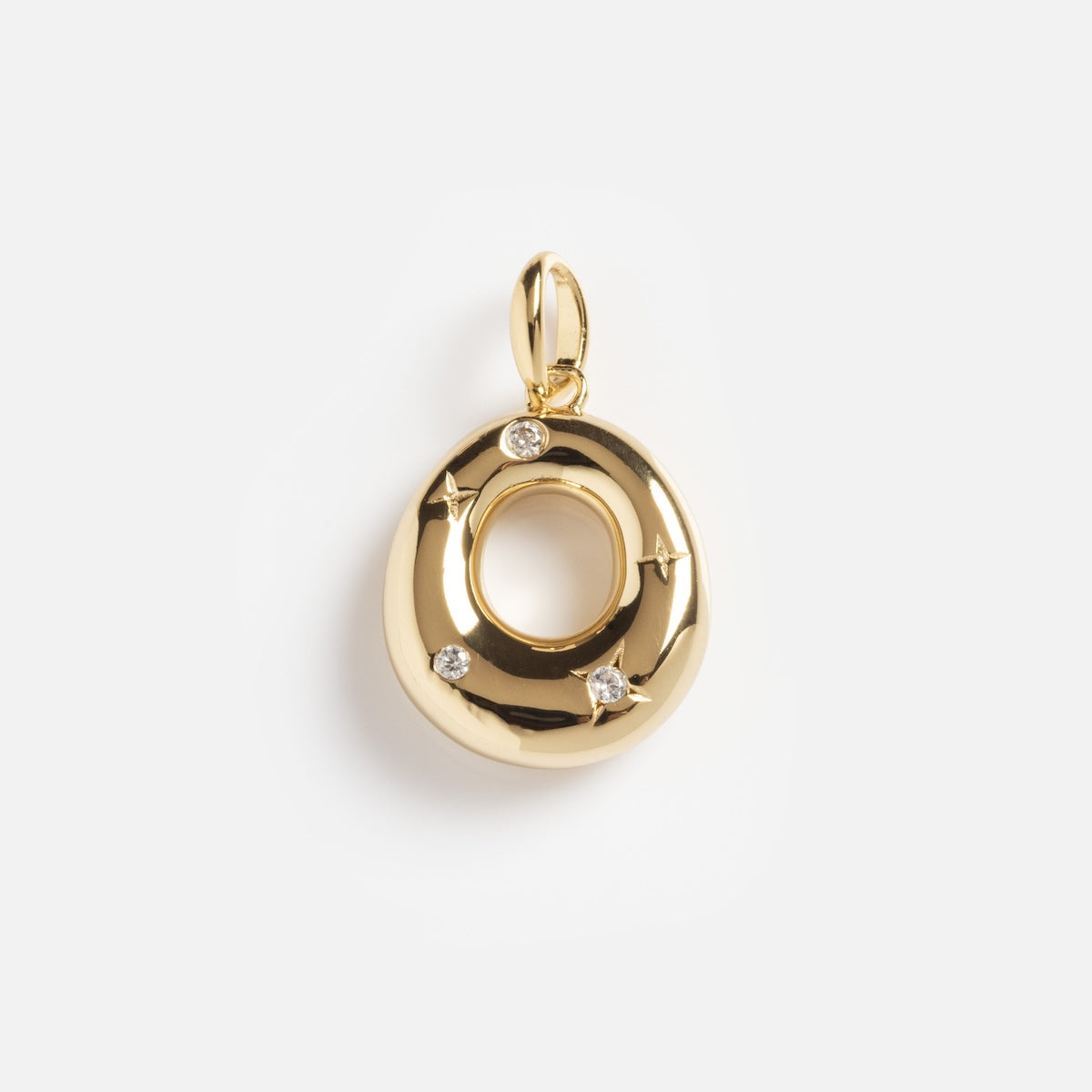 The Star Crossed Celestial Bubble Letter Charm is an oval-shaped gold pendant with a smooth, shiny finish, featuring four small embedded diamonds and a top loop for necklaces, shown on a plain white background.