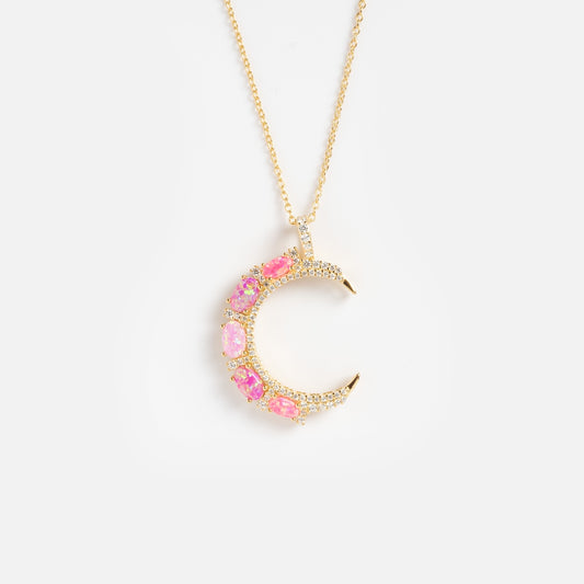 The Pink Opal Crescent Moon Pendant features pink and iridescent gemstones set in a gold crescent moon, elegantly hung on a fine gold chain and shown against a plain white background.