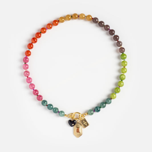 The Beaded Gemstone Charm Holder Necklace features round, multicolored stones in a gradient rainbow pattern and three small gold and black charms at the front—an eye-catching gemstone statement piece.