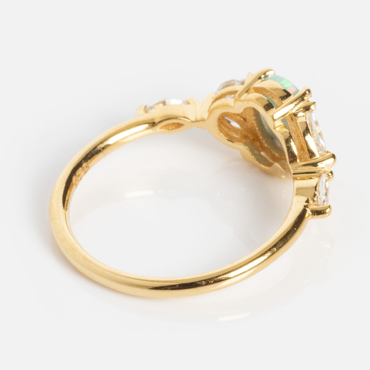 The Pink Opal Gum Drop Ring features a striking pink opal in the center, flanked by two smaller clear stones on each side, displayed from an angled side view against a white background.