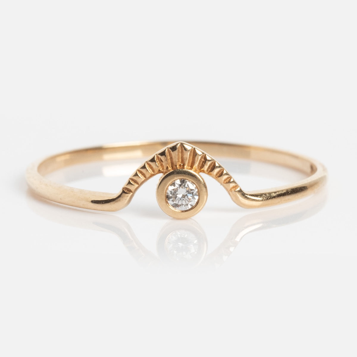 The Corrie Ring is a delicate gold band with a textured wave design, highlighted by a single round diamond set in the center beneath its elegant raised curve.