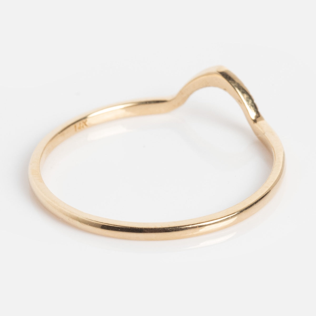 The Cairn Ring is a thin, gold band featuring a subtle wave-shaped curve, shown against a white background.