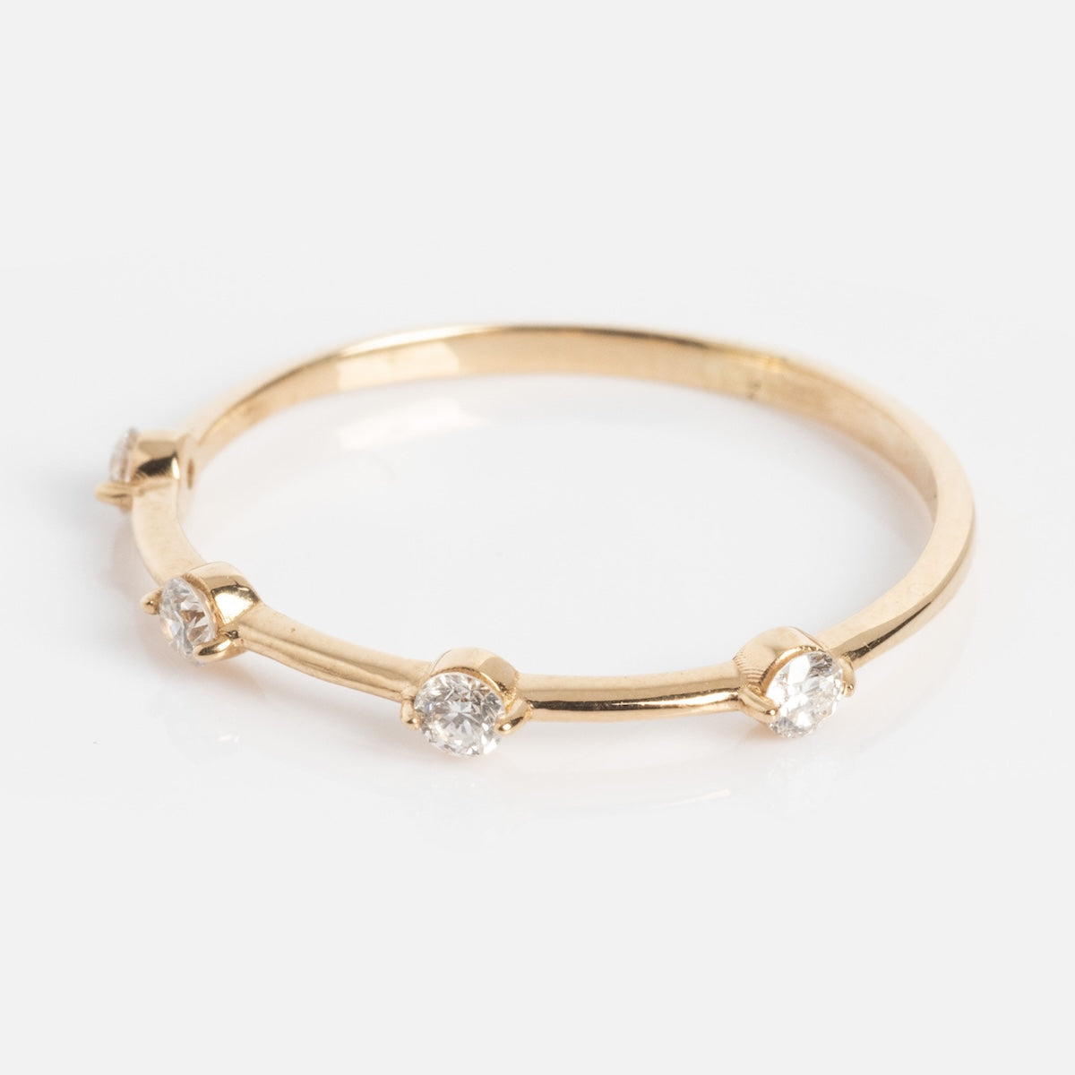 The Munro Ring is a slim gold band with five evenly spaced round diamonds set in small prongs around the band, shown on a white background.