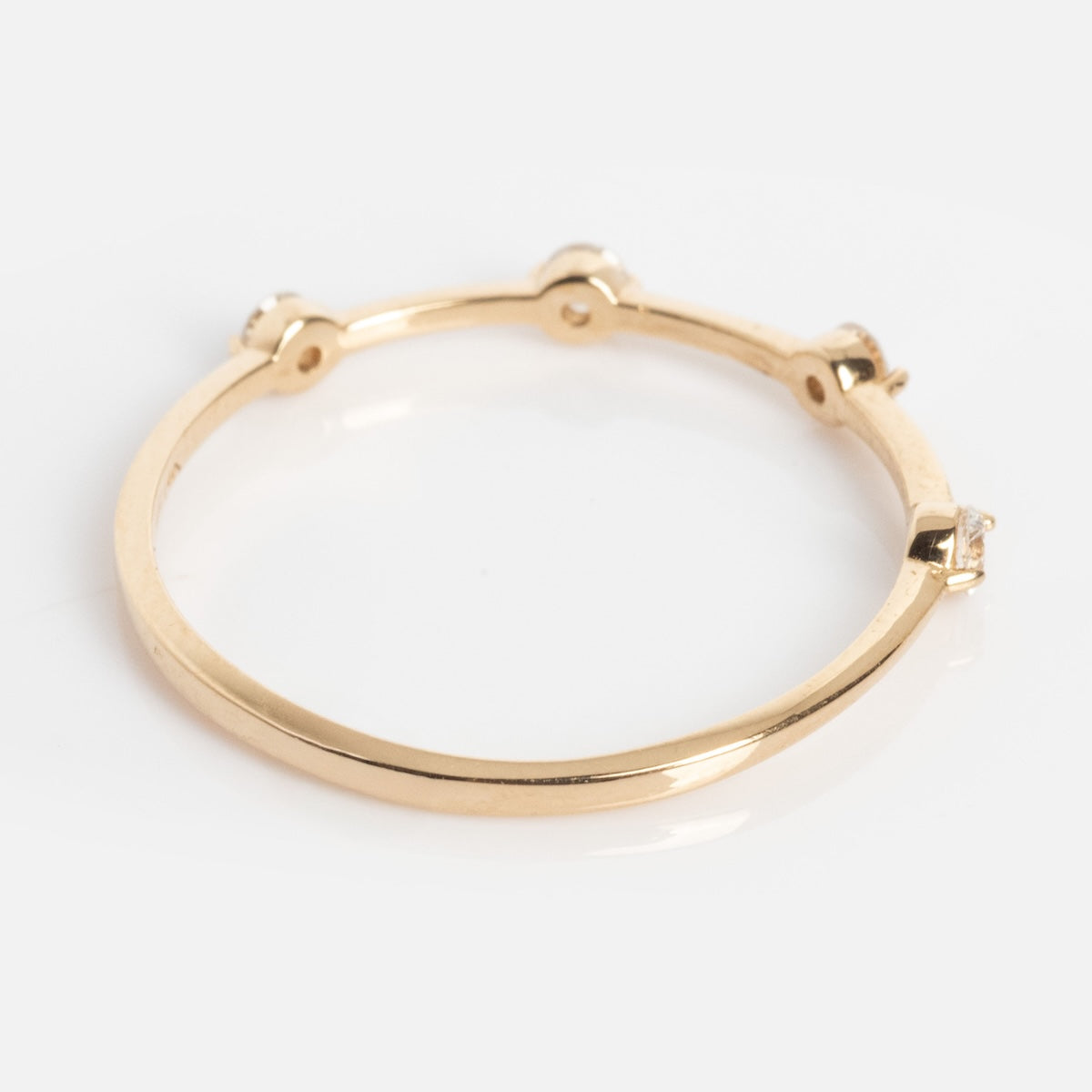 The Munro Ring features a simple gold band with four evenly spaced round clear gemstones set on top, shown against a plain white background.