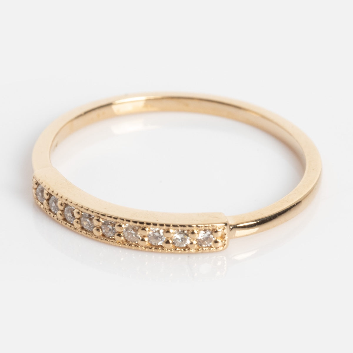 The Clyde Ring is a slim gold band with a row of small, round white gemstones set in a straight line on the top half, displayed on a simple light background.