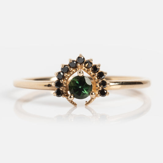 The Tosia Tourmaline Ring features a central round bi-color tourmaline set in solid gold, accented by a fan-shaped semicircle of small black diamonds.
