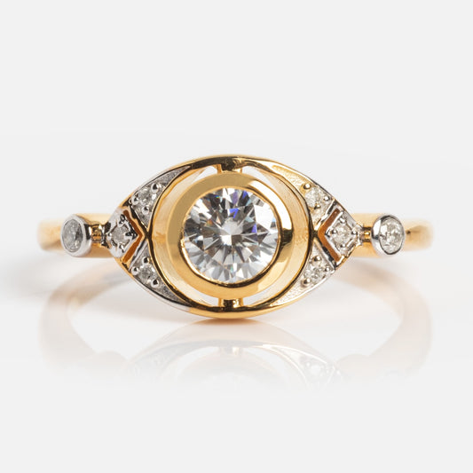 The Vienna Moissanite and Diamond Ring showcases a large central round stone, accented by crescent and geometric shapes with smaller diamonds on each side, all set against a plain white background.