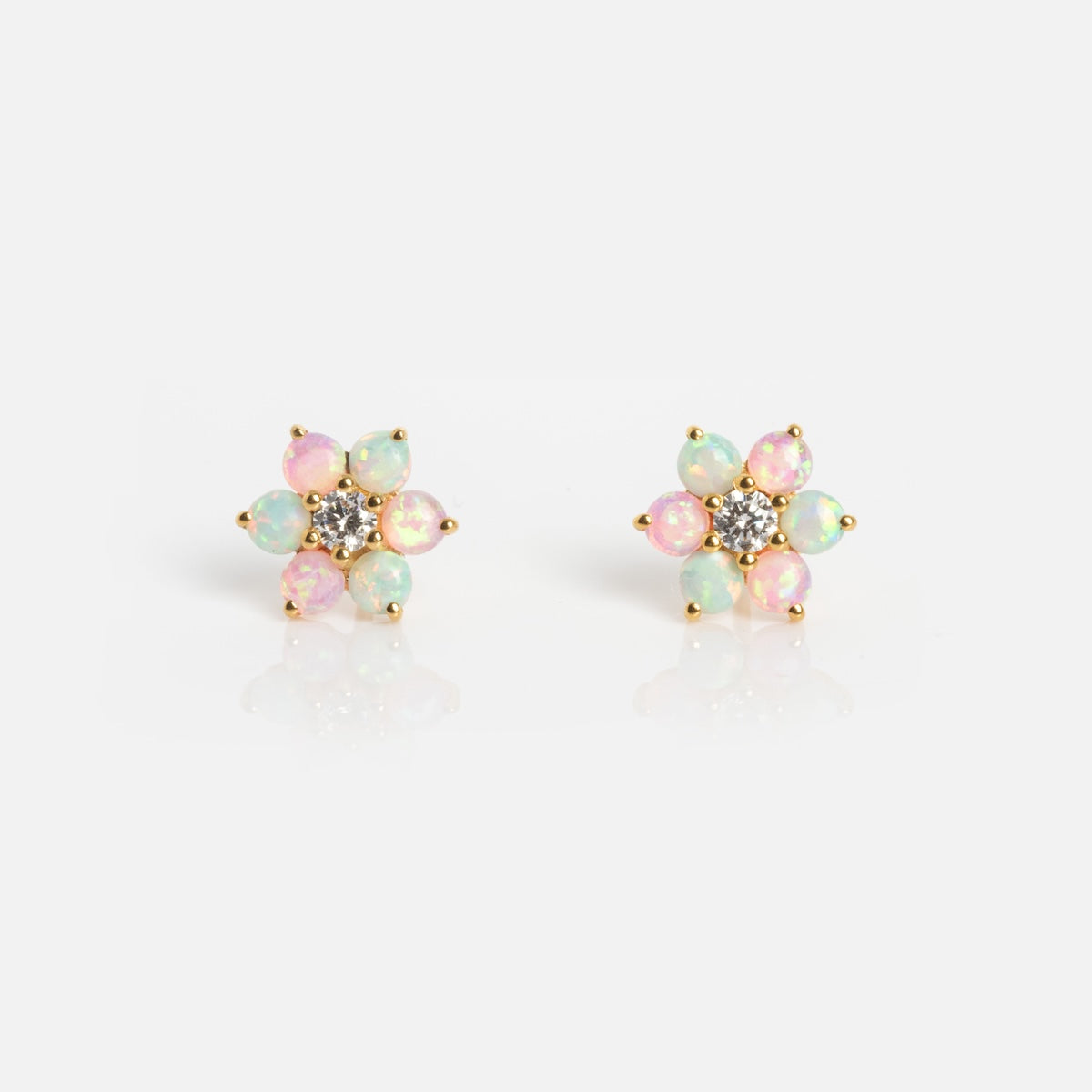 The Tropical Opal Fleur Studs are flower-shaped earrings with round pink and green opal petals, gold settings, and a central cluster of small clear stones, shown against a white background.