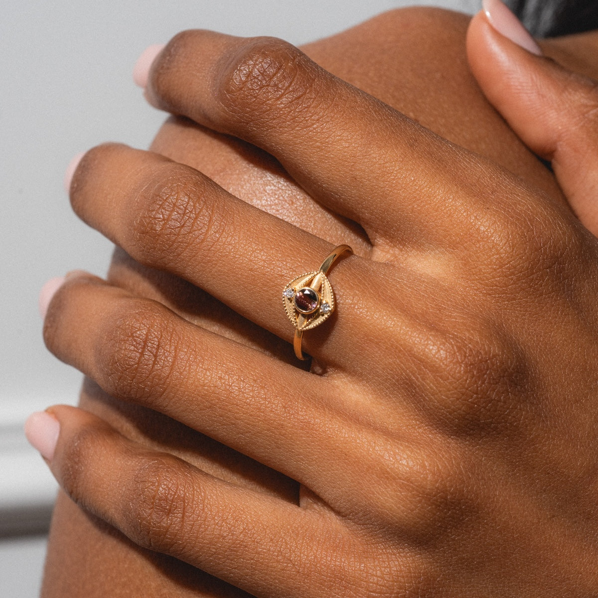 A close-up of a hand with neatly manicured nails wearing the Staffa White Diamond Ring, featuring sparkling white diamonds, gently resting on another hand.