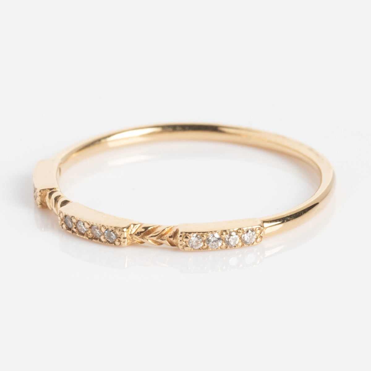 The Roxburgh Ring is a delicate gold band adorned with small, sparkling diamonds set in three sections across the top, showcased on a white background.