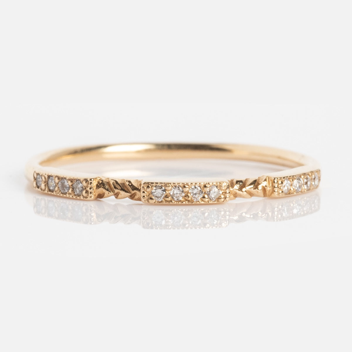 The Roxburgh Ring is a delicate gold band adorned with small, evenly spaced round diamonds and subtle textured accents between each stone, shown on a white background.