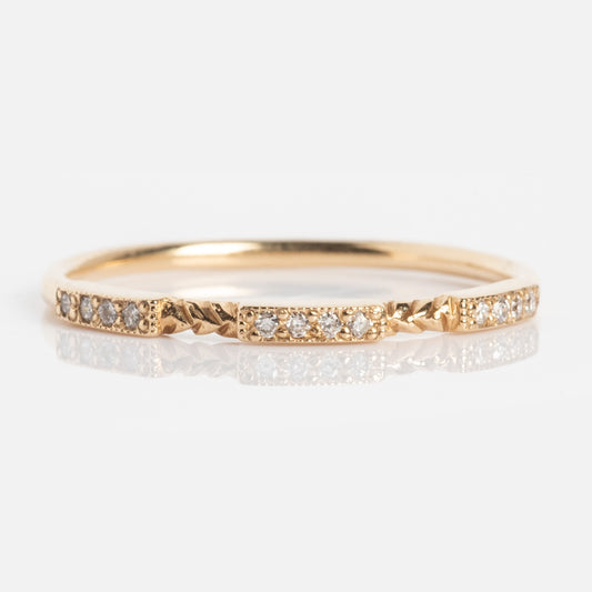 The Roxburgh Ring is a delicate gold band adorned with small, evenly spaced round diamonds and subtle textured accents between each stone, shown on a white background.