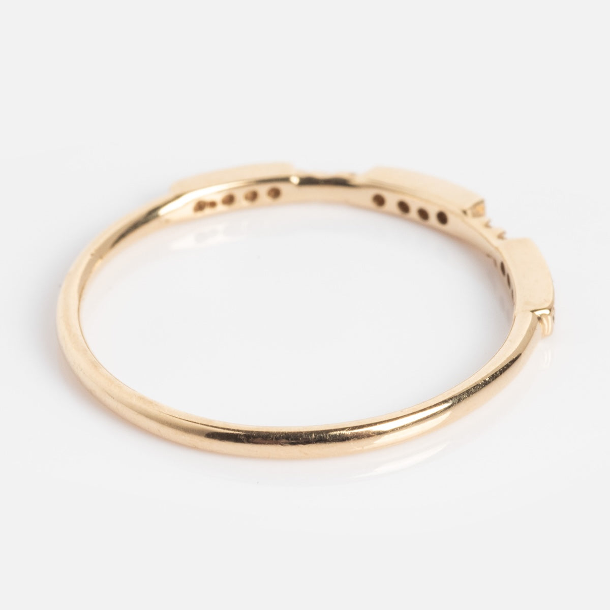 The Roxburgh Ring is a simple, thin gold band featuring small rectangular accents, shown against a plain white background.
