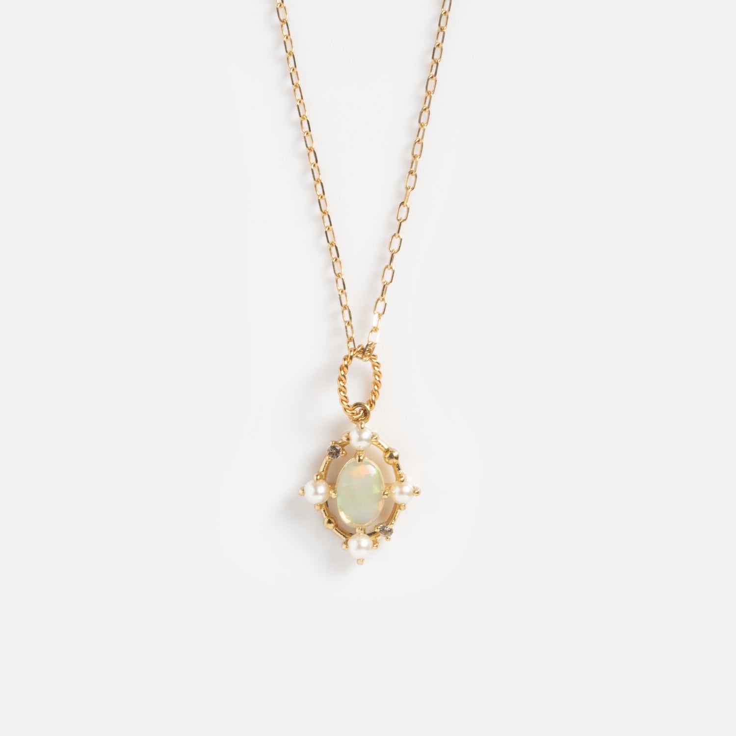 The Solid Gold 2025 October Capsule Opal Statement Set features an oval opal pendant in a twisted gold frame, accented with white pearls, and comes with a free gift. Displayed on a plain white background.