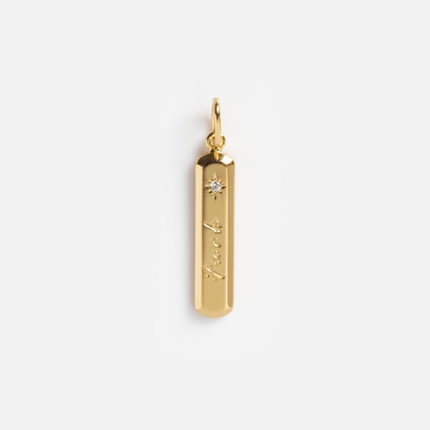 The Curse Word Charm is a 14k gold plated necklace with a vertical rectangular pendant, rounded edges, "luck" engraved on it, and a small gemstone accent near the top.