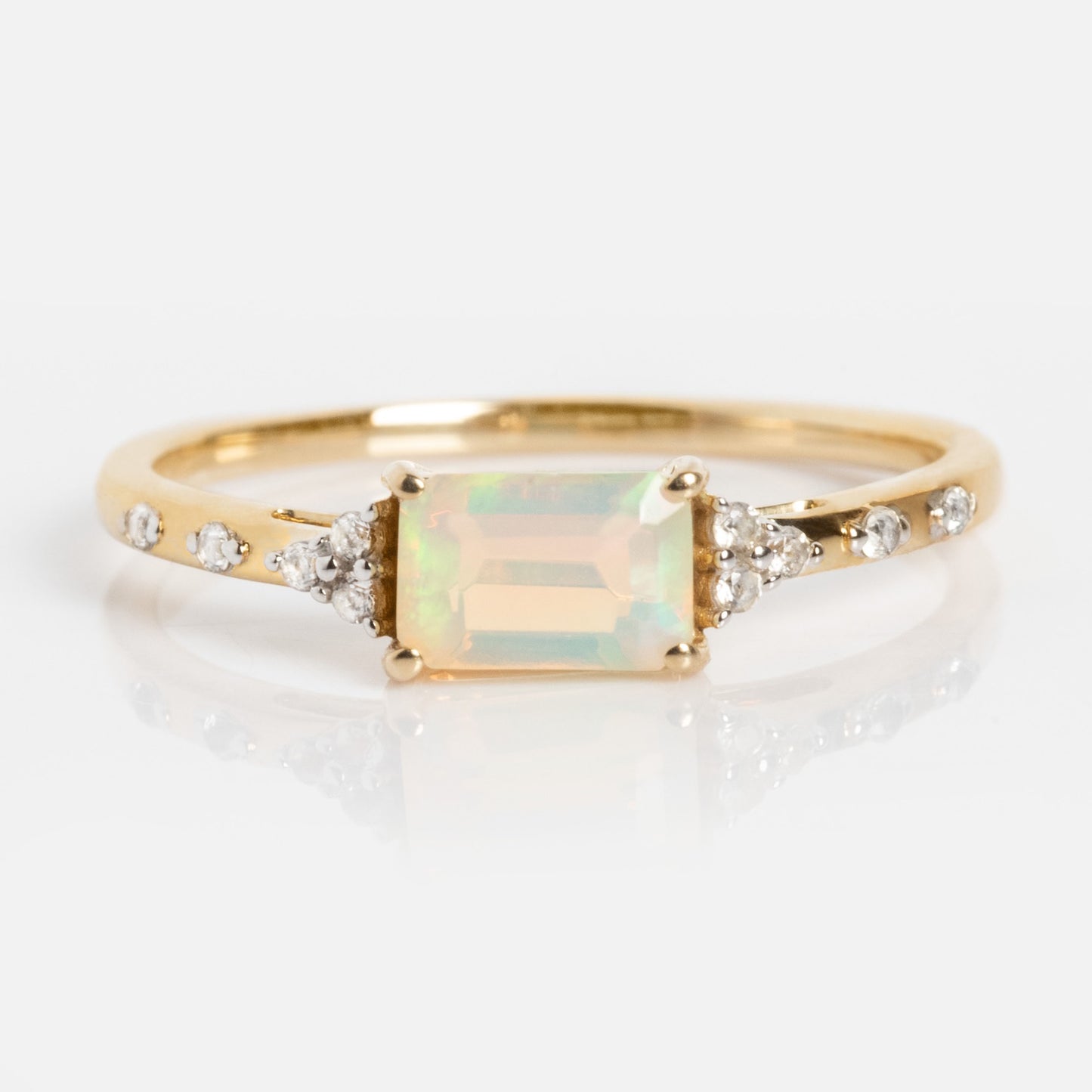 The Solid Gold Glimmering Birthstone Baguette Ring features a rectangular opal center stone, flanked by round diamonds and accented with additional diamonds along the band for a sparkling touch.