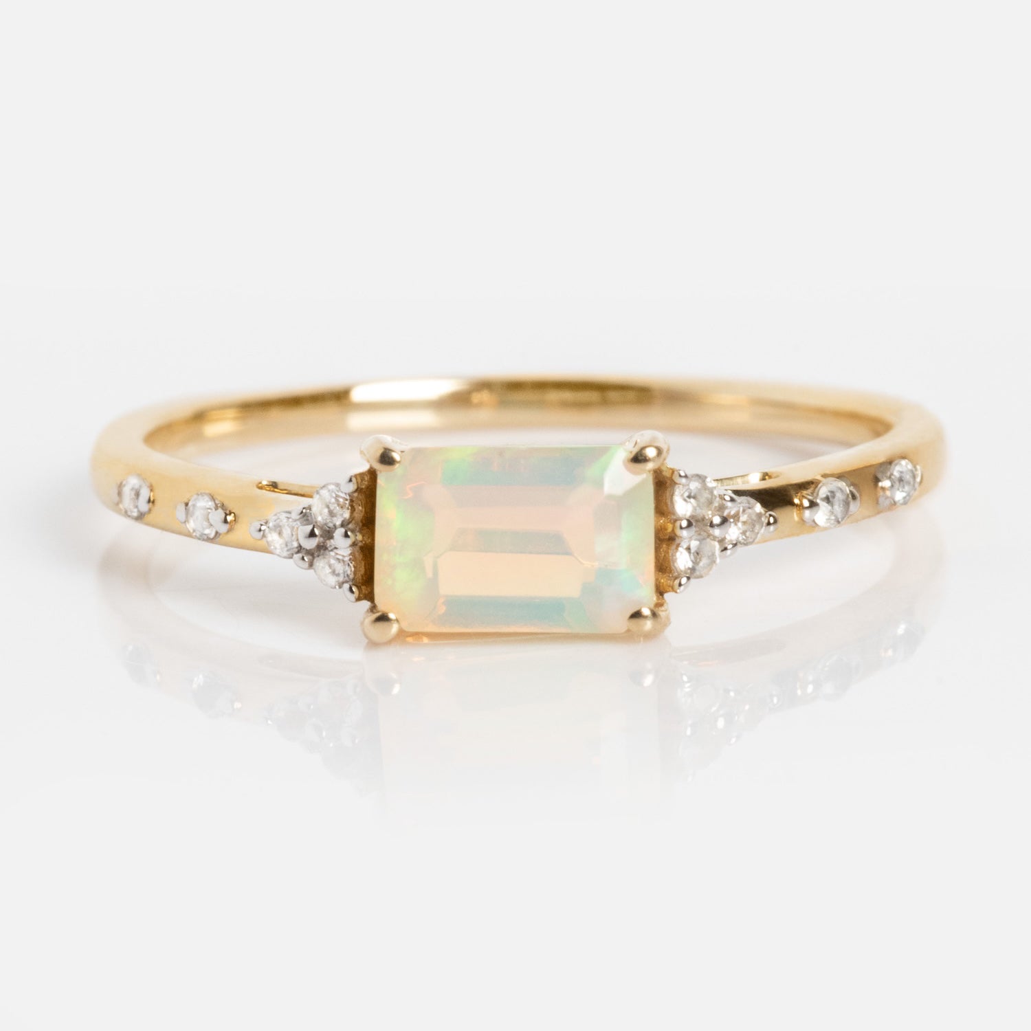 The Solid Gold Glimmering Birthstone Baguette Ring features a rectangular opal center stone, flanked by round diamonds and accented with additional diamonds along the band for a sparkling touch.