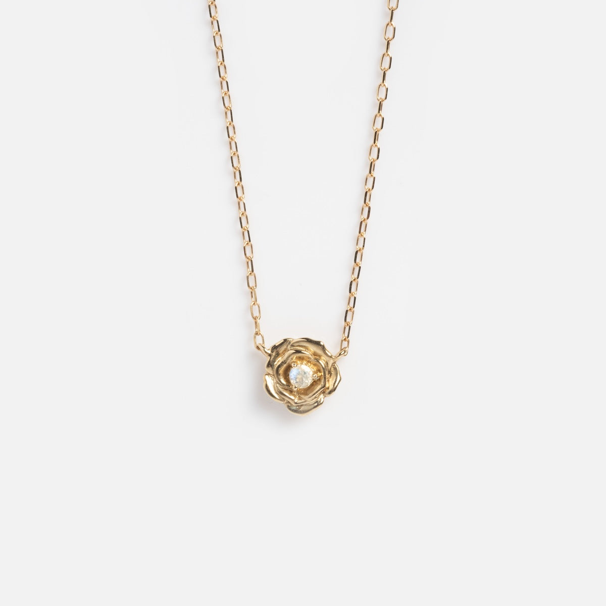 The Solid Gold Birth Flower Bloom Necklace features a delicate gold chain and a flower-shaped pendant with a gemstone center, shown on a plain white background.