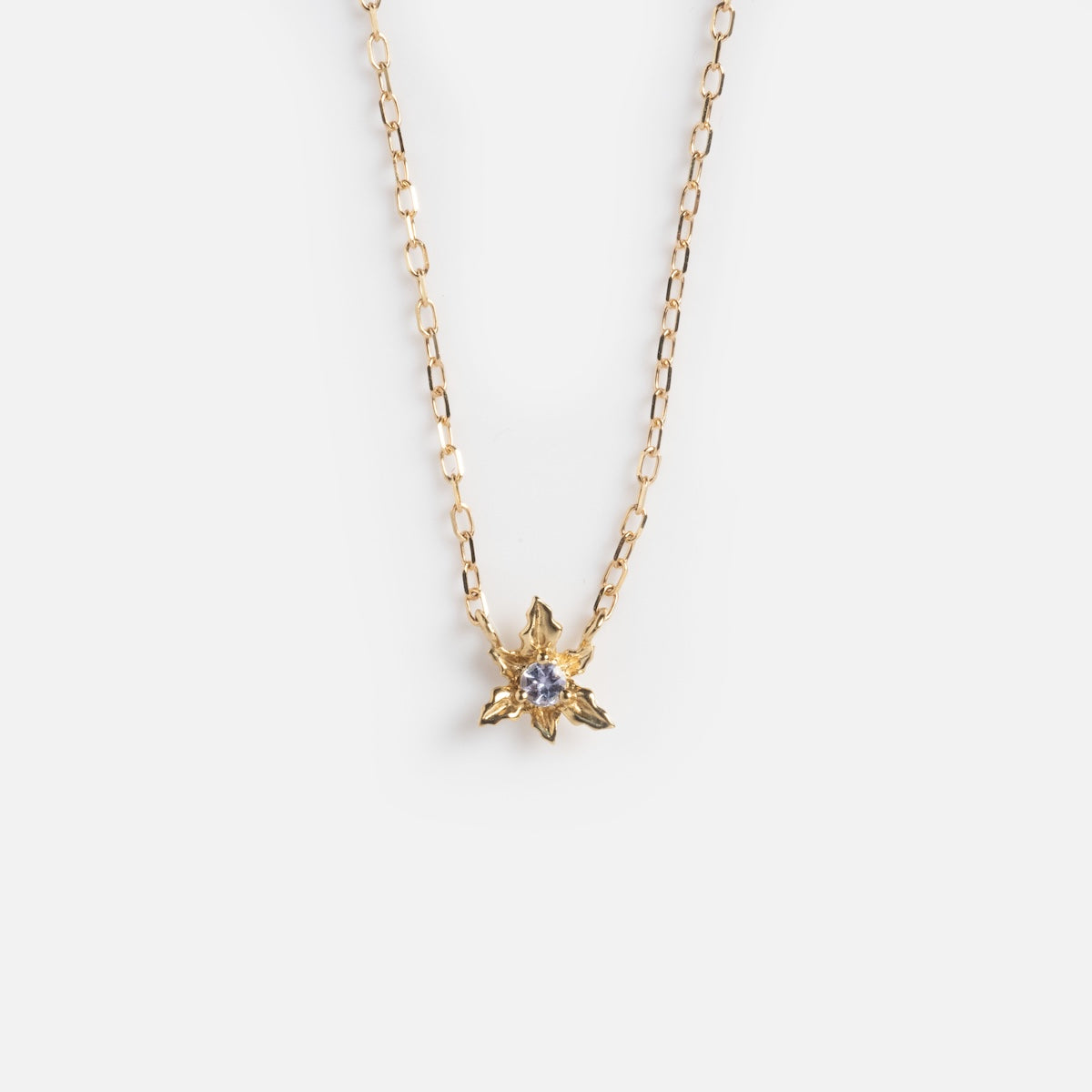 The Solid Gold Birth Flower Bloom Necklace is a delicate gold chain featuring a birth flower pendant with a clear gemstone at the center, shown on a plain white background.