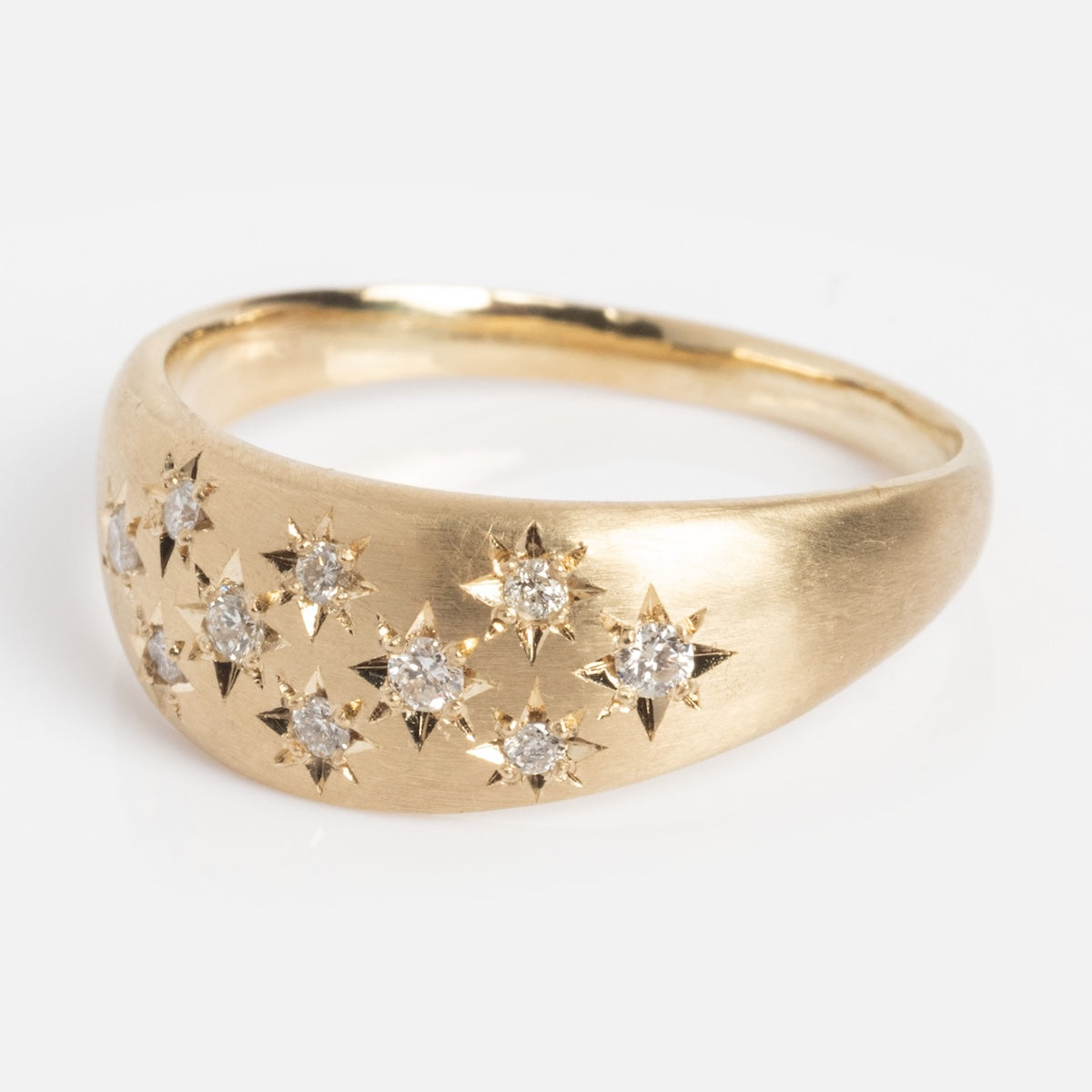 The Half Moon Bombe Ring is a gold band with a gentle dome, adorned with small diamonds set in star-shaped engravings on the top.