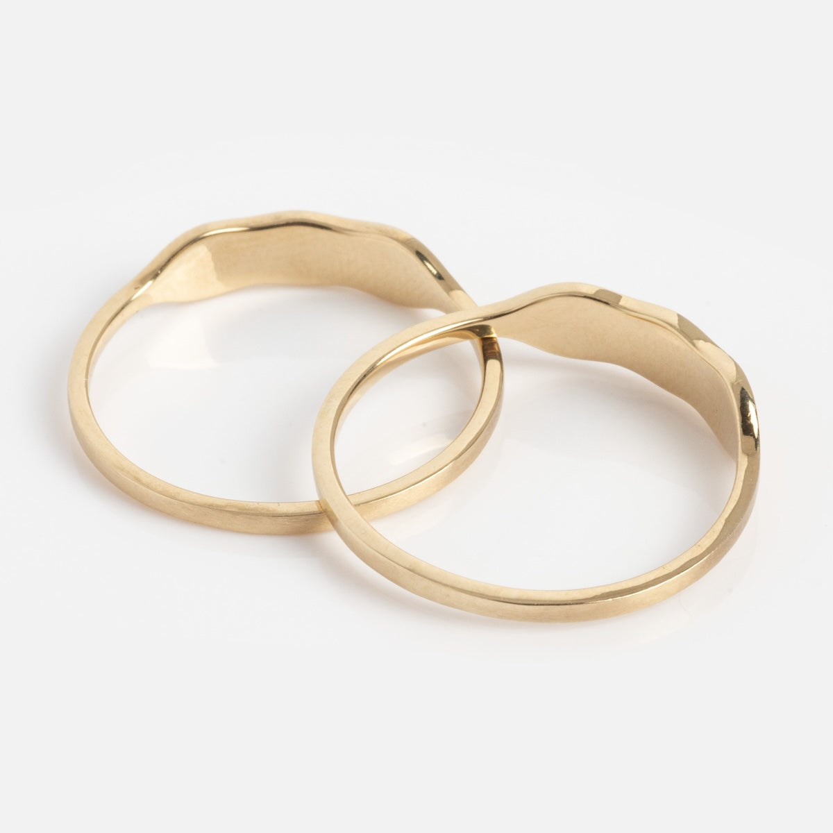 Two 14k Ripples Customizable ID Bands with organic-shaped, slightly irregular gold bands are placed side by side on a white surface.