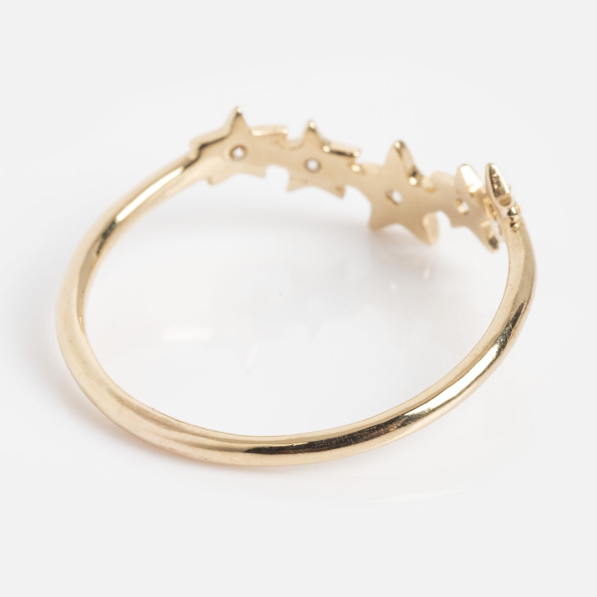 The Stars Aligned Band is a delicate gold ring with a row of small, connected star shapes on one side, shown on a plain white background.