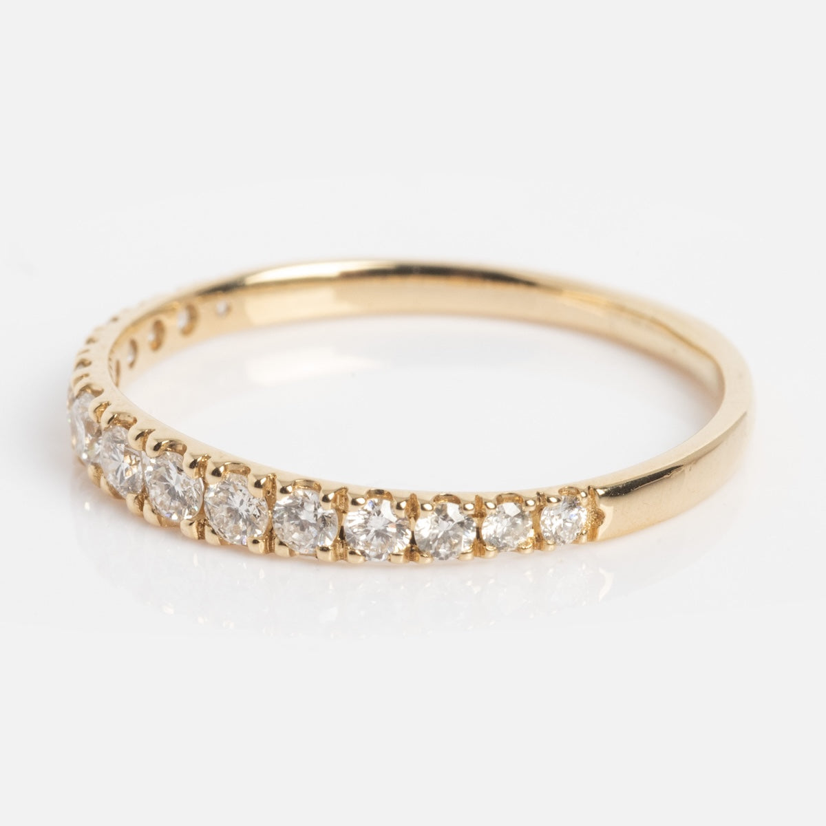 The Echo Diamond Band is a slim gold ring with a row of round, sparkling white diamonds set along the top half of the band, shown against a white background.
