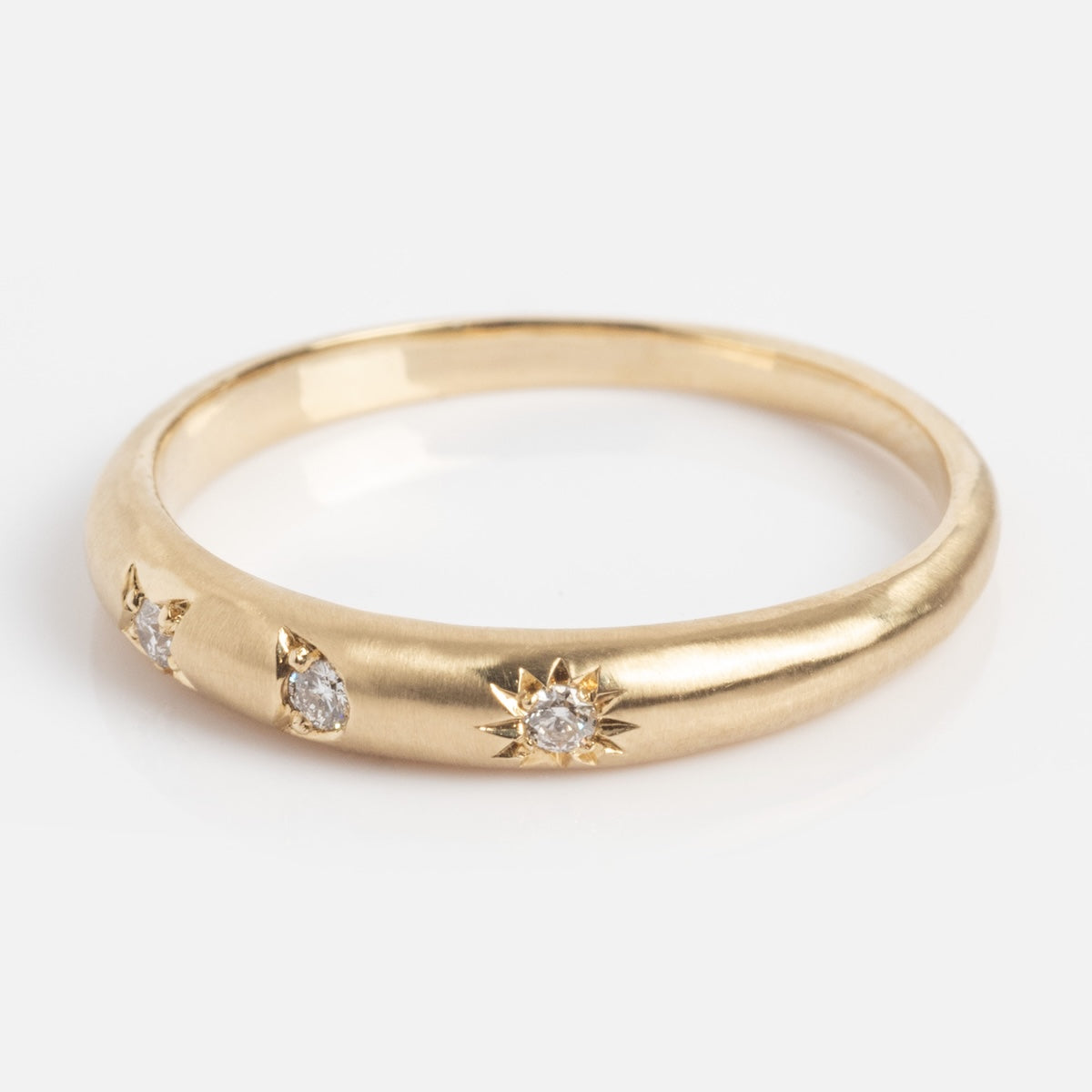 The "You are my Sun, Moon and Star Band" is a gold ring with a smooth matte finish, accented by three small diamonds in starburst and teardrop-shaped bezels, shown on a white background.