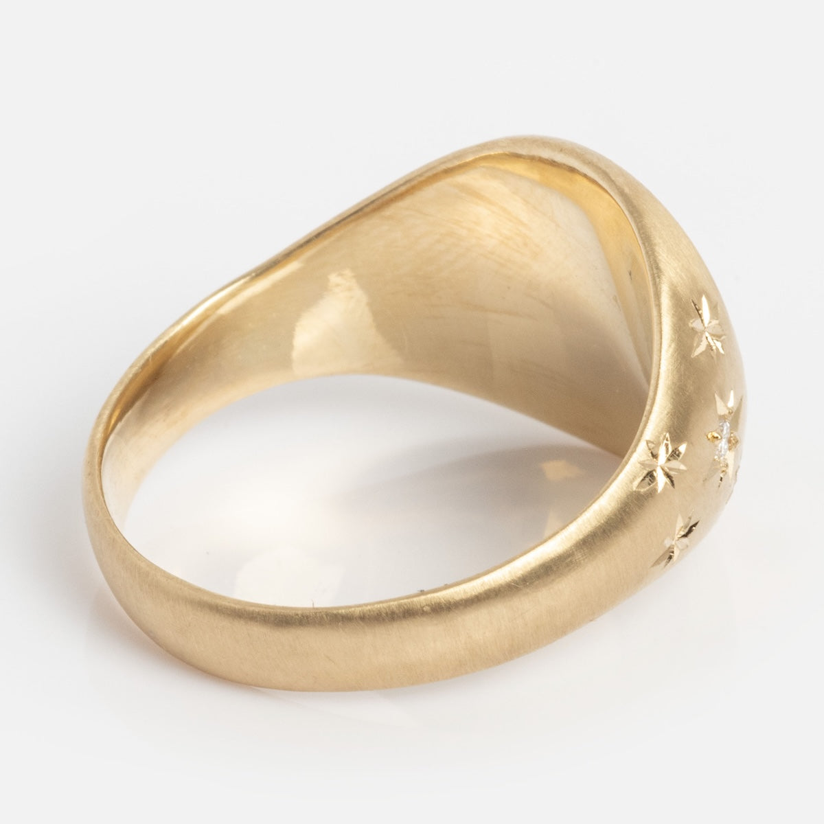 A smooth gold Till Death Do Us Part Signet with Diamonds, oval-shaped and featuring small engraved stars set with tiny diamonds on one side, photographed on a white background.